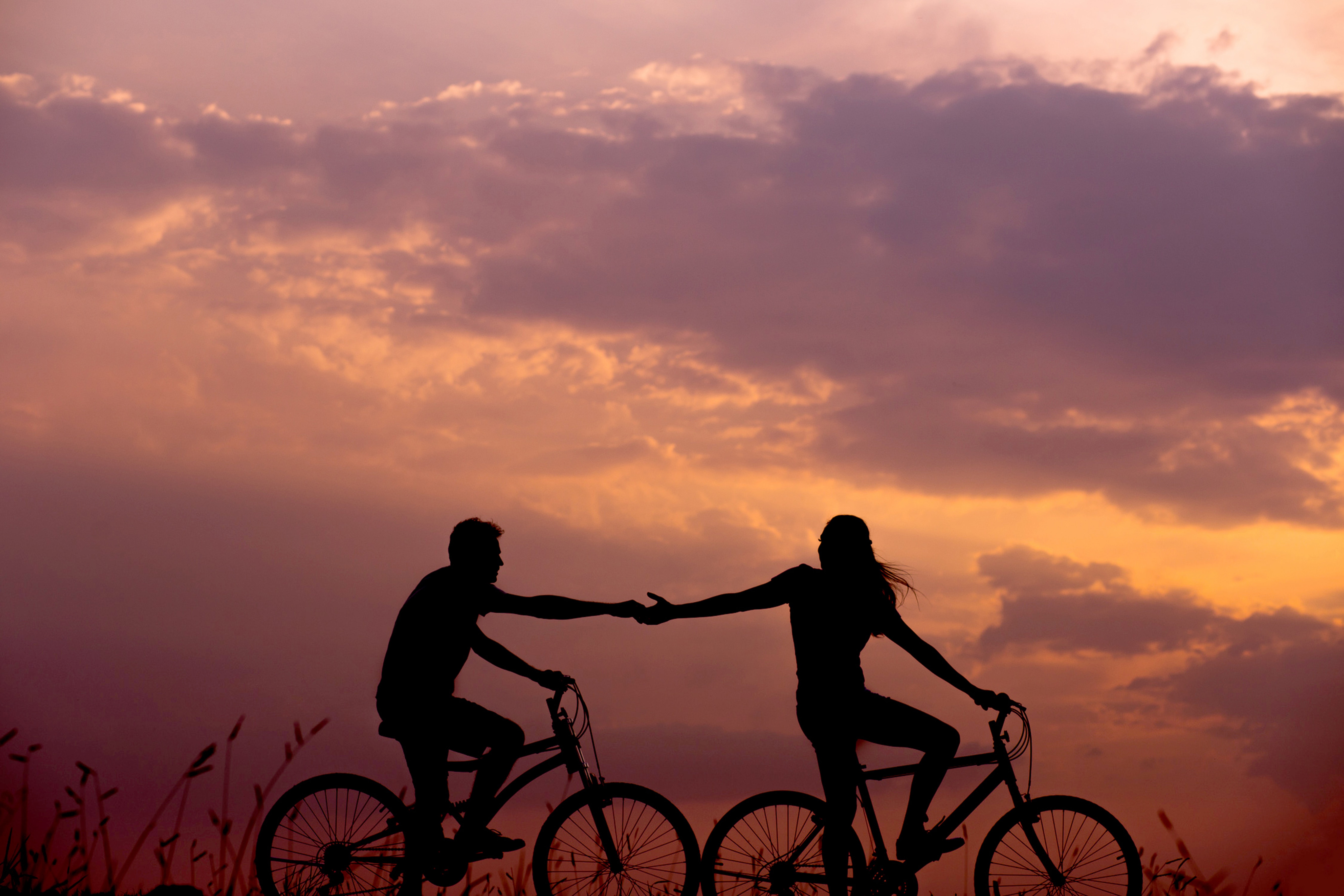 two friends riding on bikes during sunset