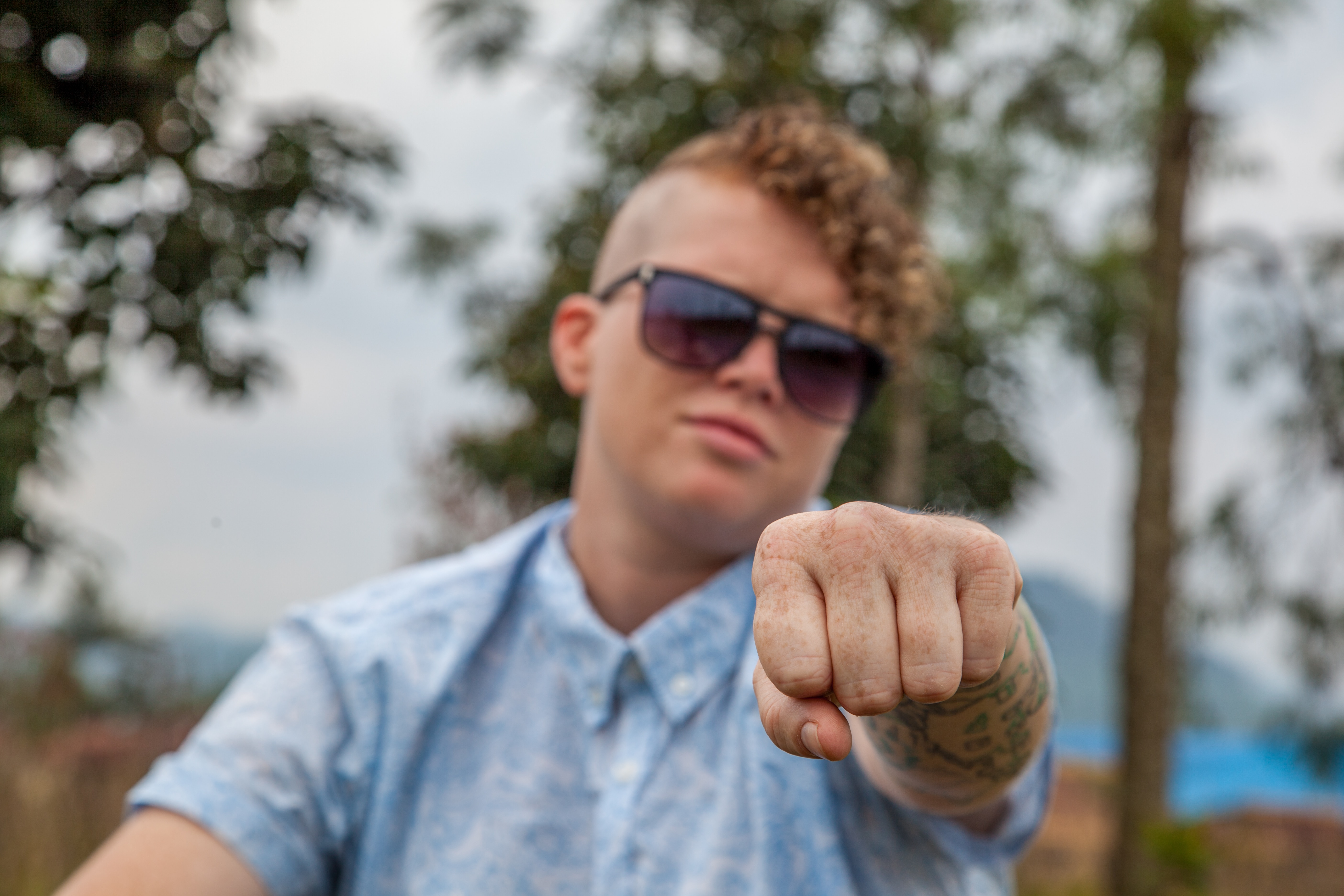 young man wearing sunglasses offering a fist bump
