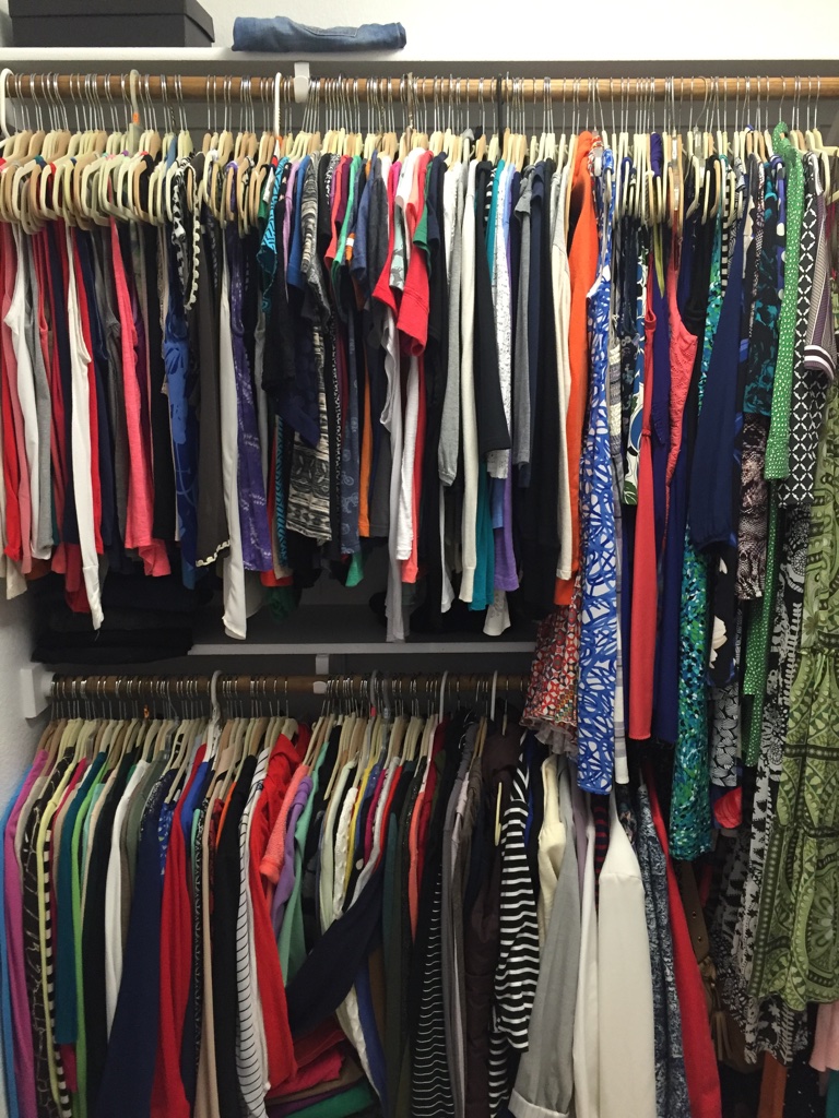 lots of colorful clothes hanging in a closet.
